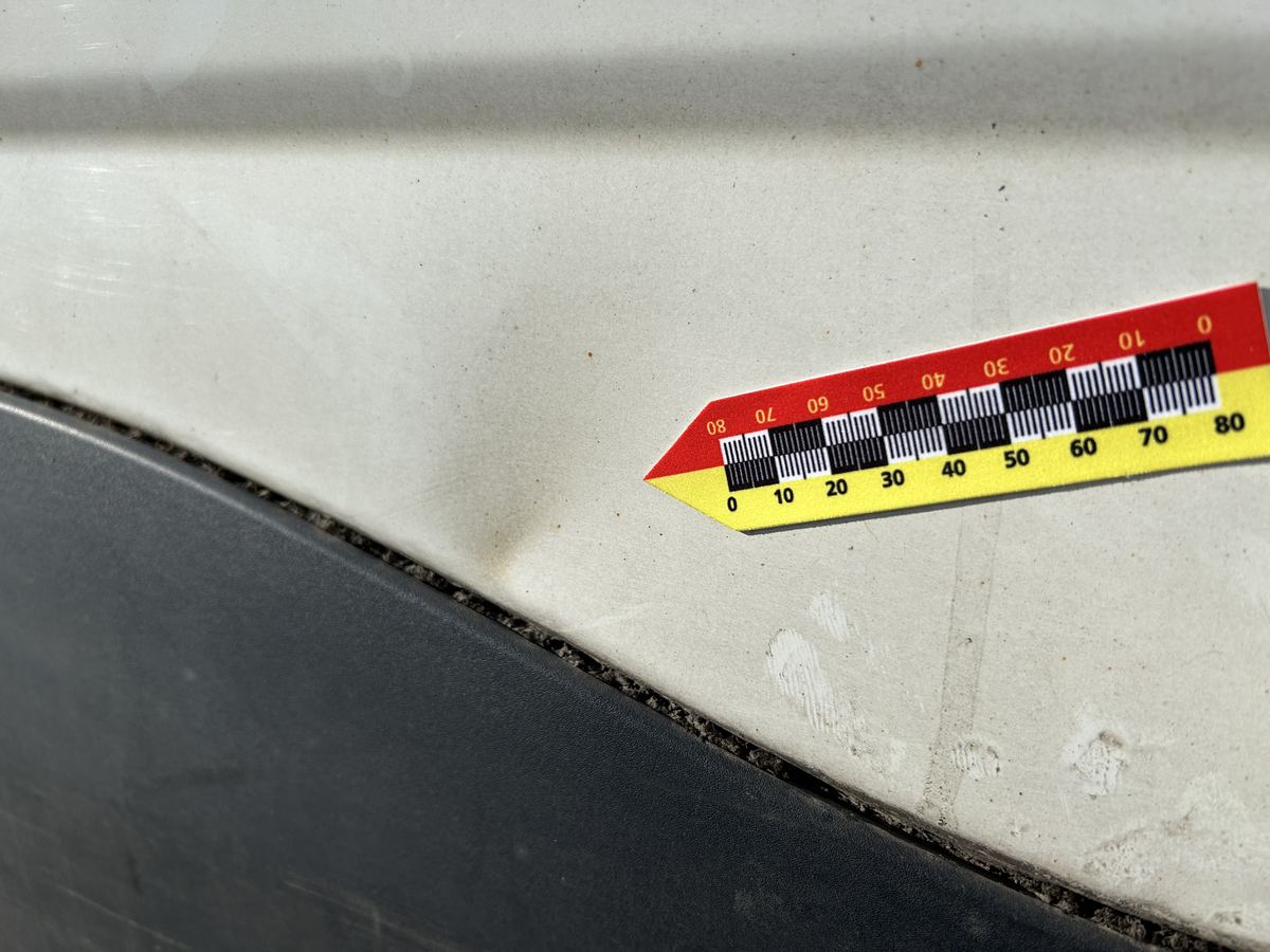 Eingedrückte rechte Seitenwand eines weißen Iveco Daily Kastenwagens mit angelegtem Maßstab, Schadenhöhe 7.686,01 €